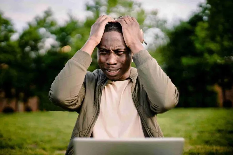 Disappointed man outdoors with a laptop.